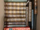 many books in a box that are stacked on top of each other