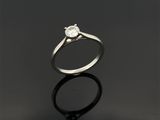 une bague en diamant à pierre unique posée sur un fond noir