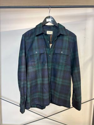 une chemise à carreaux bleus et verts suspendue à un cintre