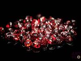 some red glass beads on a black surface with a black background