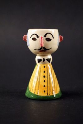 une petite tasse en céramique sur laquelle sont représentés un visage et un nœud papillon