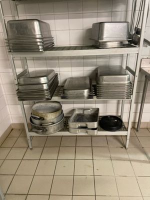 many pans and pans on a metal shelf in a kitchen
