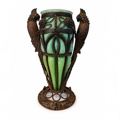 un vase vert surmonté de deux oiseaux
