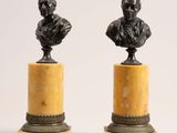 a pair of bronze busts of a man and a woman on marble bases