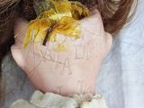 a close up of a doll ' s face with a yellow flower on it