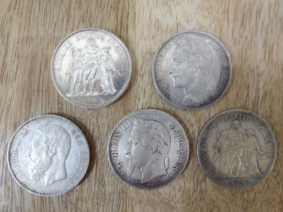 quatre types différents de pièces d'argent posées sur une surface en bois