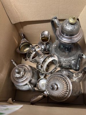 a box full of silver teapots and other silverware