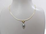 Collier plaqué or orné d'une perle grise, présenté autour du cou d'un mannequin