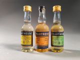 three bottles of liquor sitting on top of a table next to each other
