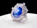 a close up of a blue sapphire and diamond ring on a white plate
