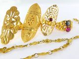 un collier en or et une paire de boucles d'oreilles posés sur un fond blanc