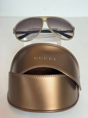 Des lunettes de soleil Gucci et leur étui posés sur une table blanche, sur fond blanc