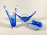 two blue glass vases sitting next to each other on a white surface