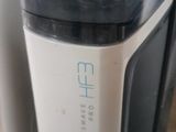 a water dispenser sitting on the floor next to a trash can