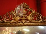 un miroir avec un cadre doré, sur lequel est posé un vase doré