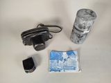 a camera, a canister, and a cigarette on a table