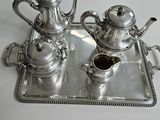two silver teapots on a tray on a table