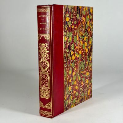 an old book with a red cover sitting on top of a white table