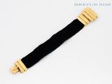 an image of a black and gold bracelet on a white surface