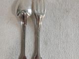 deux cuillères en argent et une fourchette posées sur une nappe blanche