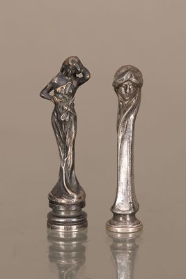 deux figurines en argent représentant une femme et un homme, posées sur une table