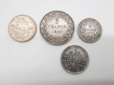 quatre types différents de pièces d'argent sur une surface blanche