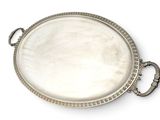an oval silver tray with a handle and handles on a white surface