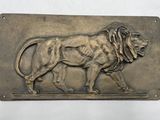 une plaque métallique sur laquelle est représenté un lion couché sur le flanc