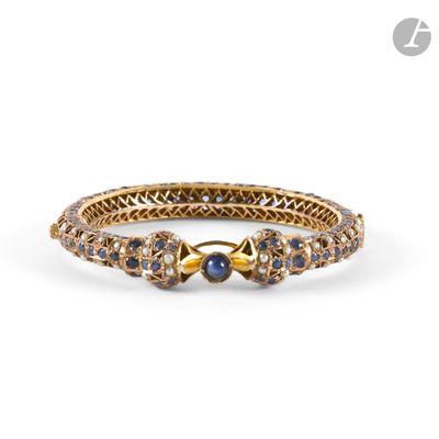 a close up of a gold bracelet with blue and white stones
