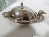 une assiette en argent ornée d'un oiseau, posée sur une serviette