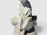 statue d'un garçon assis sur un rocher, un livre à la main
