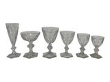 six glass goblets and a wine glass on a white background