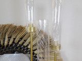 a glass vase and a gold candle holder on a wicker table
