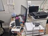 a cluttered desk with a laptop, printer, cell phone and other office supplies