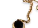 an image of a gold necklace with a black stone on it
