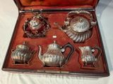 a silver tea set in a case on a table