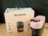 a pink coffee maker sitting on a table next to a box