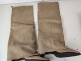two pairs of brown sued boots hanging on a white wall
