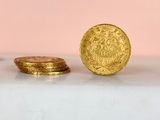 two gold coins sitting on top of a white table next to each other