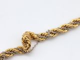 a close up of a gold chain with a knot on it