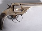 Un vieux pistolet est posé sur une table devant un fond blanc.