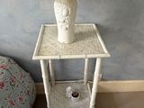 une table blanche sur laquelle est posée une lampe, à côté d'un lit