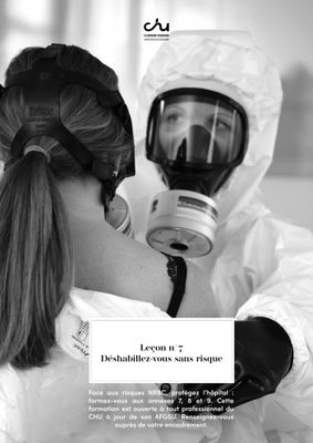 La femme porte une combinaison de protection et tient un masque à gaz.
