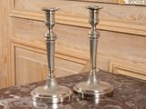 deux bougeoirs en argent posés sur une table en marbre