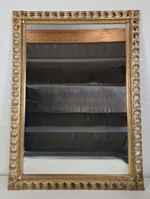 an ornate gold framed mirror on a white wall next to a shelf