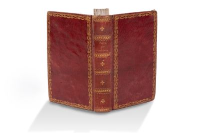 un vieux livre à la couverture rouge posé sur une surface blanche