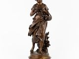 une statue en bronze représentant une femme tenant un panier de fleurs