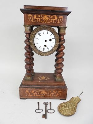 une petite horloge en bois avec un pendule et une paire de ciseaux à côté