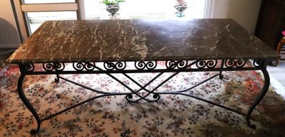 une table au plateau en marbre posée sur un tapis devant une fenêtre