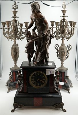 une statue représentant une femme tenant une horloge devant un lustre